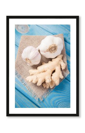 Garlic bulbs with ginger on blue wooden table. Concept of natural medicine.