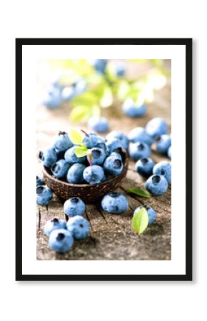Organic blueberries with green leaves over rustic wooden table