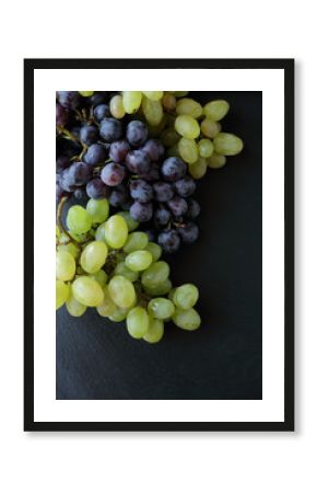 two branches of grapes on slate