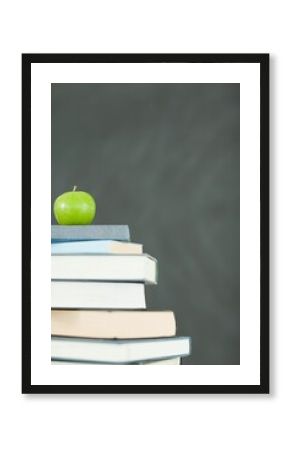 Green apple in front of blackboard on books