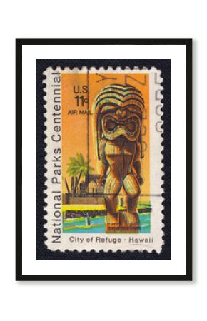 Old vintage cancelled postage stamp printed in the USA circa 1972 shows Kii Statue and Temple, City of Refuge at Honaunau, Hawaii. Macro image of the stamp on a black background.