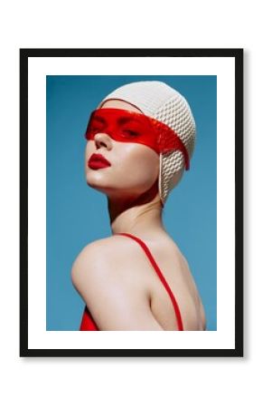A self-confident stylish young woman in a white swimming cap and red glasses looks at the camera arrogantly. Headshot in the studio