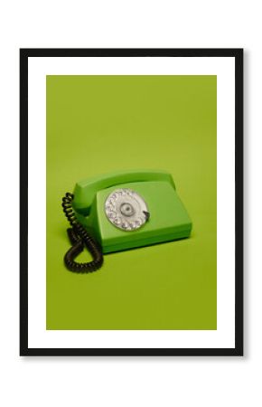 Vintage green rotary phone on bright green background. Concept of retro communication, nostalgia, vintage style. Suitable for creative poster design, banner, tech history campaign.