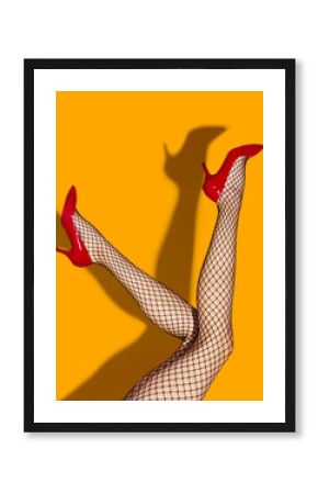 Contemporary art collage. Female slim legs in fishnet socks and red heeled shoes on bright yellow background. Pop art photography. Vivid colors. Concept of creativity, imagination, artwork, lgbt, fun.