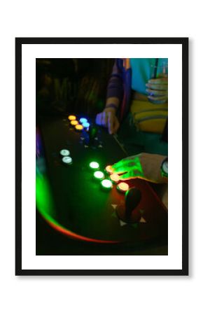 Playing games on an arcade machine in an arcade room, hands pressing buttons