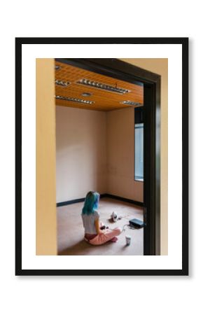 Trendy blue haired woman playing video game on floor at home