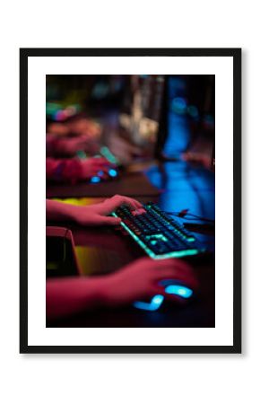 Close-up of the gamers hand movements on the glowing keyboard and mouse