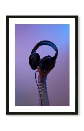 Hands with black headphones on violet background.