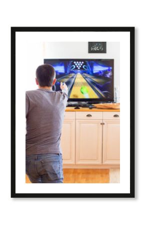 A man playing video game without joystick at home. Cheerful father with family playing bowling and having fun with new trends technology. Gaming concept